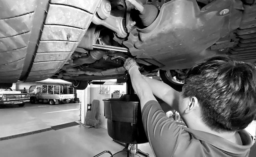 A Man Servicing The Exhaust Pipe Of A Car