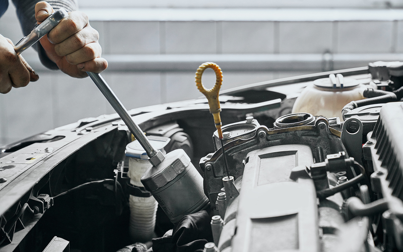 Mechanic using tools to inspect engine during car diagnostic check.